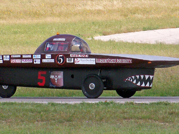 A solar car featuring a streamlined design and shark-mouth paint on the track.