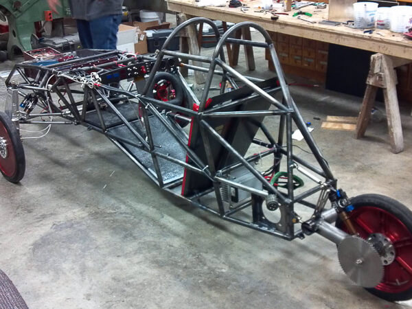 Metal framework of a solar car with three wheels in a workshop.