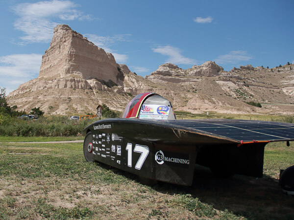 Solar-powered race car number 17 with a rocky desert landscape in the background.